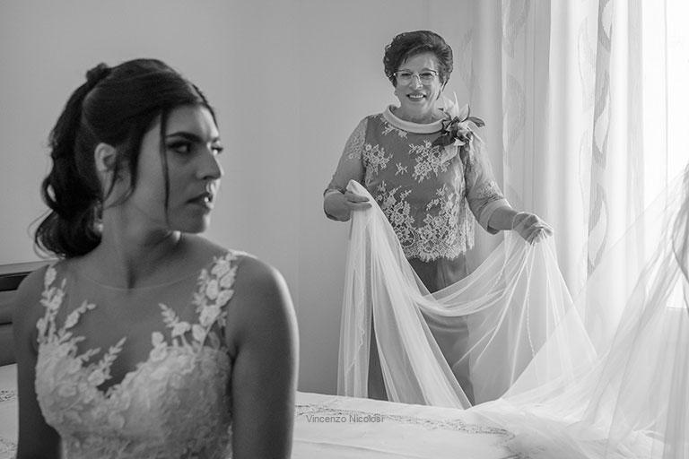 La fotografia di matrimoni a Sciacca, la mamma della sposa prepara il lungo velo bianco